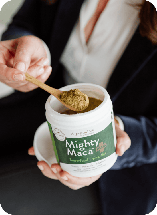 Person scooping Mighty Maca superfood powder with a spoon from a container.