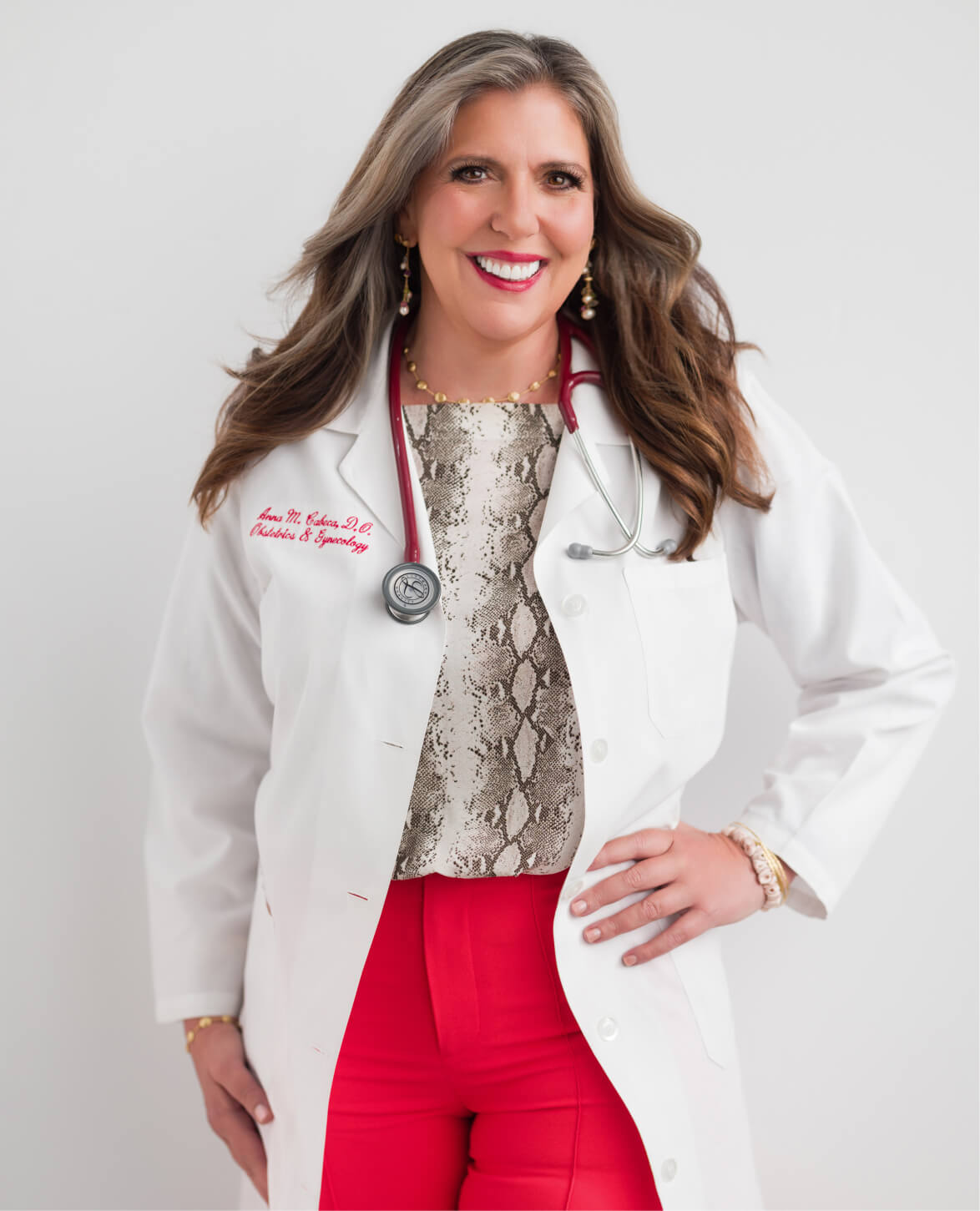 Dr. Anna Cabeca in a white medical coat with a stethoscope, smiling against a plain background