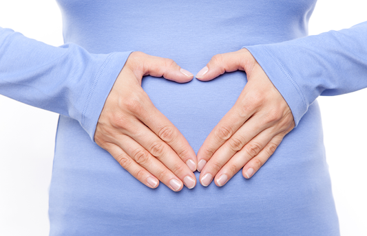 Woman's hands making a heart shape over her belly