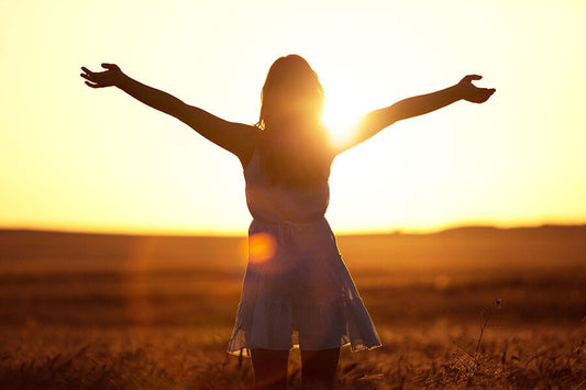 Woman with arms wide looking toward the sun