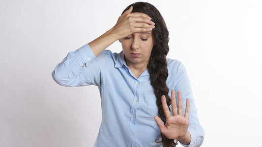 Woman with hand on her forehead, other hand says stop