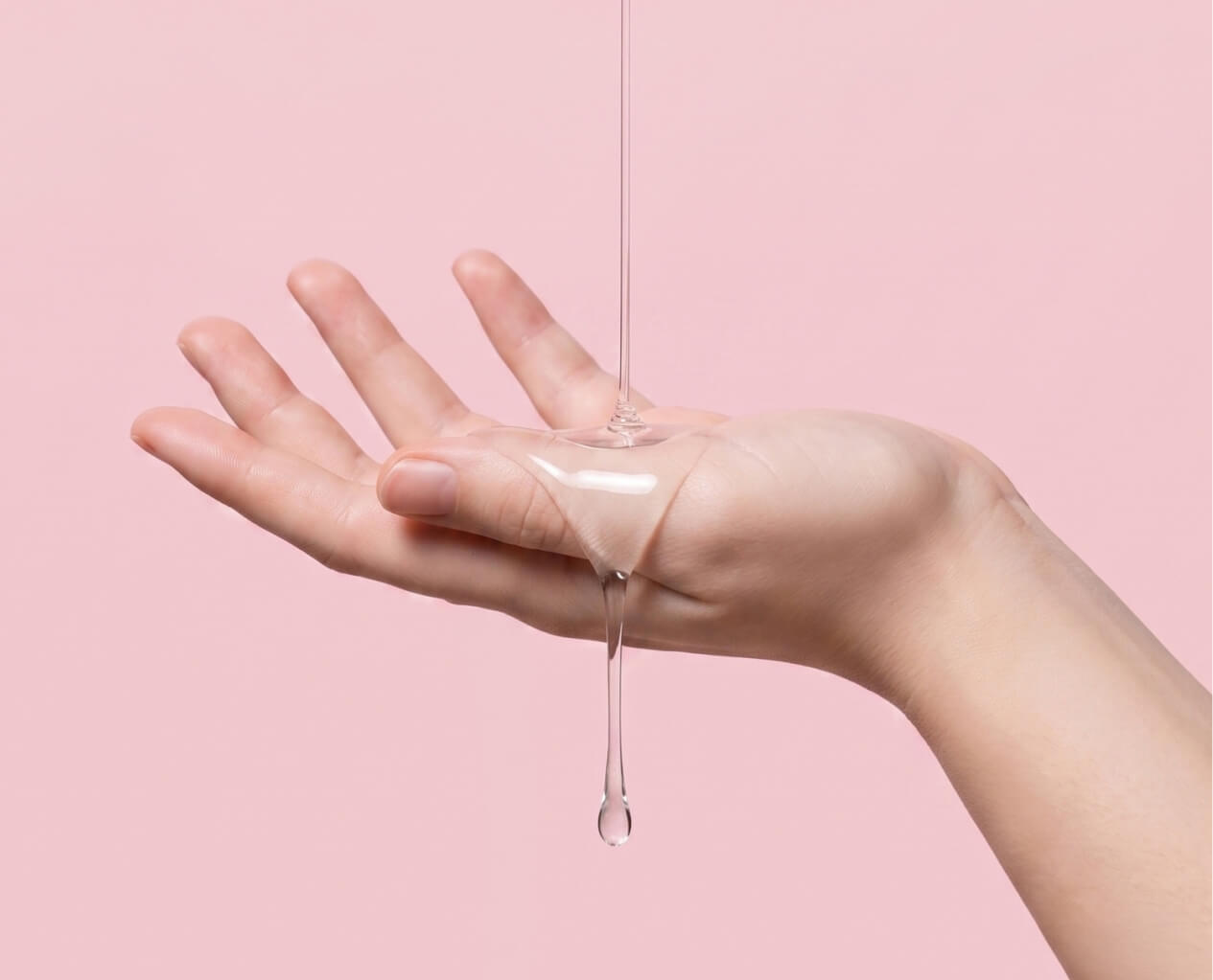 Hand receiving a drop of clear liquid against a pink background