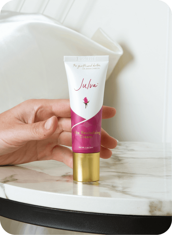 Tube of Julva cream held by a hand on a marble surface