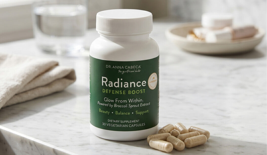 Supplement bottle labeled 'Radiance Defense Boost' on a marble surface with capsules beside it.