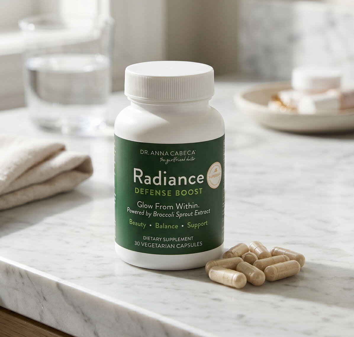 Radiance Defense Boost supplement bottle on a marble surface with capsules beside it.